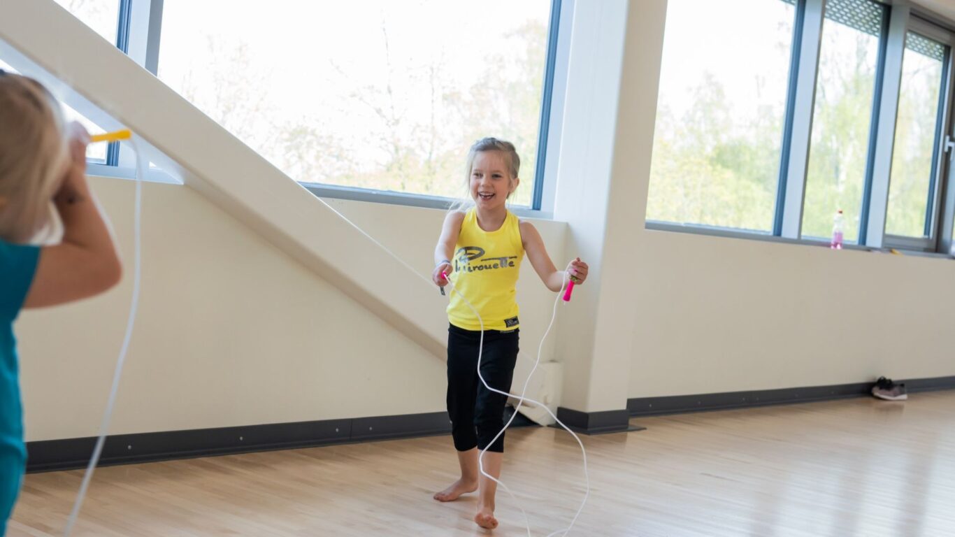 LLapsi hyppii hyppynarulla. Lapset hyppii hyppynarulla. Iloinen ilma, lapsi voimistelukoulu