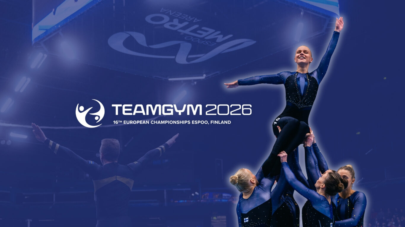 TG EM nettisivun kuva mobiili (3) Kuvassa ryhmä voimistelijoita nostaa yhden ylös, ja tämä hymyilee. Kuvassa on myös TeamGym 2026 -tapahtuman logo ja taustalla näkyy Metro Areenaa sekä yhden voimistelijan selkäpuoli.